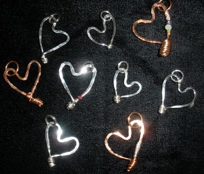 An array of heart pendants,some with copper, silver, ruby, amethyst, crystal.